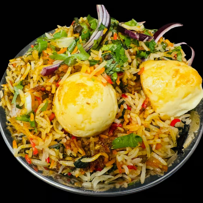 Dhaba Kitchen's Egg Biryani, a flavorful Indian rice dish with two whole boiled eggs, herbs, and spices.