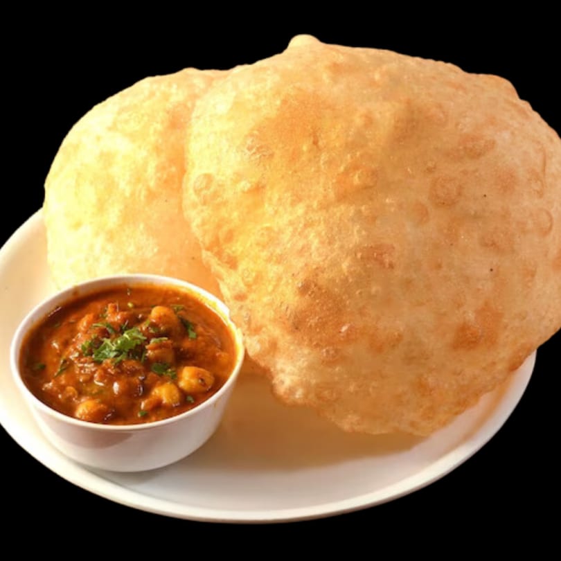 Two golden-brown Dhaba Kitchen pooris on a white plate with a side of chana masala.